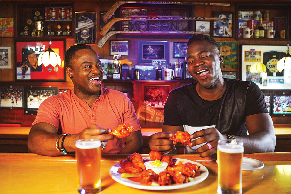 Two men eating wings at Nine-Eleven Tavern bar in Buffalo, New York (photo by Drew Brown) Two men eating wings at Nine-Eleven Tavern bar in Buffalo, New York (photo by Drew Brown)
